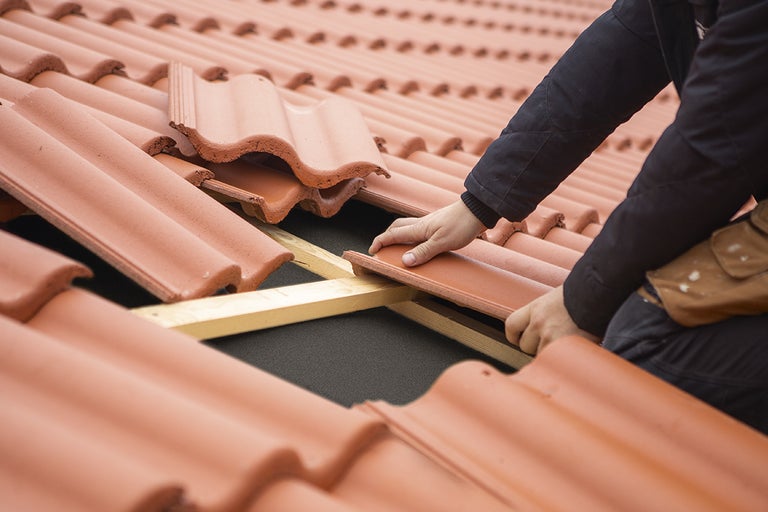 Takläggare som lägger tak med takpannor.