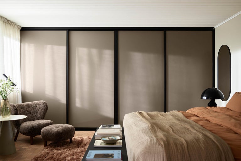 Sovrum med skjutdörrsgarderob, fåtölj och säng