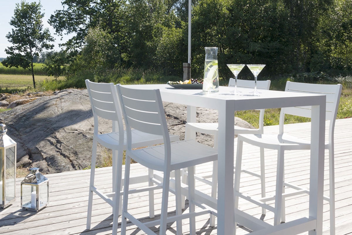 Vit trädgårdsmöbelset med bord, barstolar, glas och dekoration utomhus