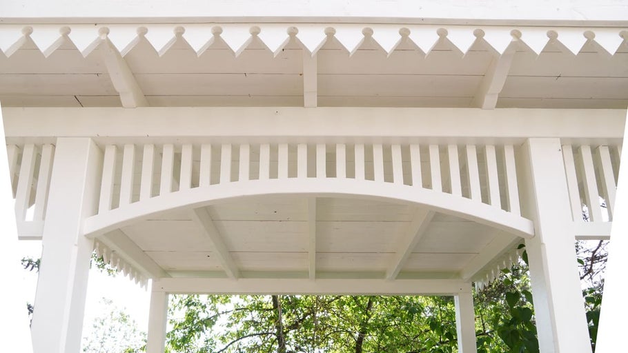 Detalj av ett vitt trädgårdspaviljong med dekorativa element