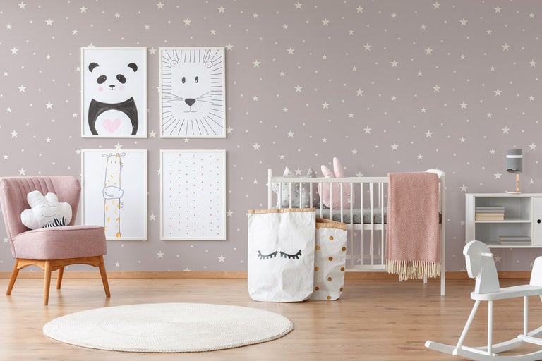 Barnrum med spjälsäng, fåtölj, leksaker och bilder på väggen med stjärntapet.