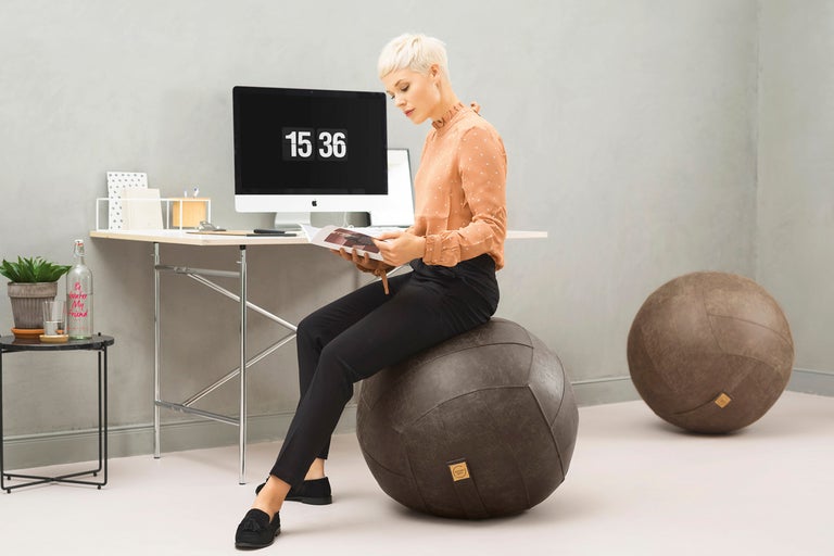 Kvinna sitter på en gymboll i ett kontor