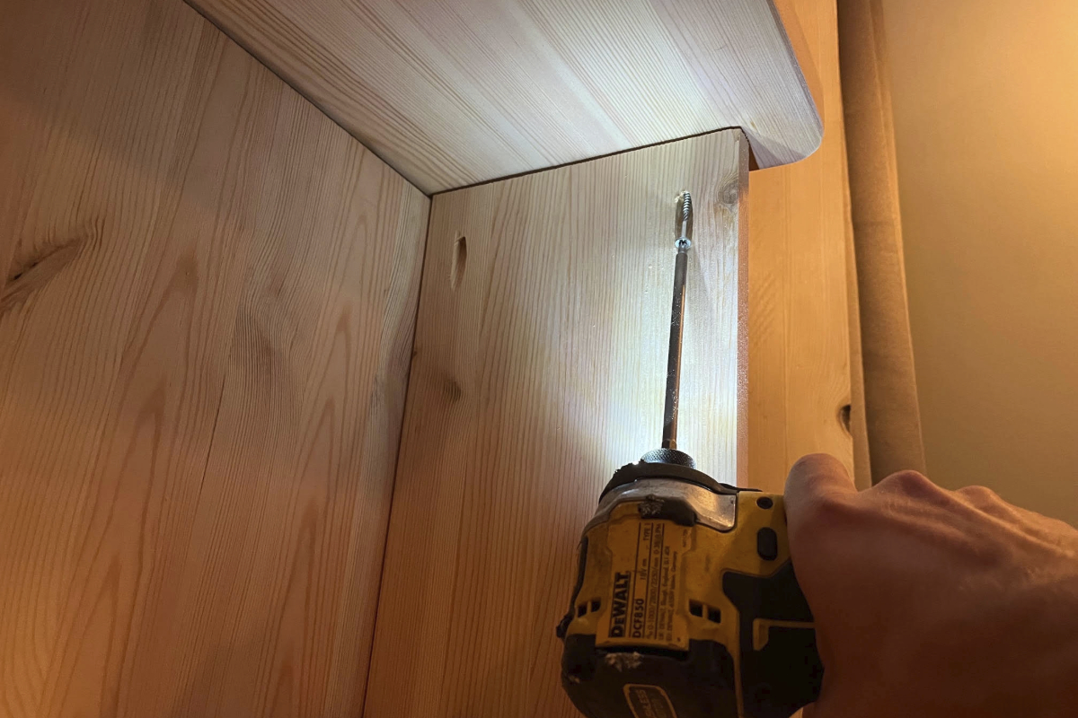 En DeWalt sladdlös skruvdragare används för att skruva in en skruv i en trämöbelpanel.