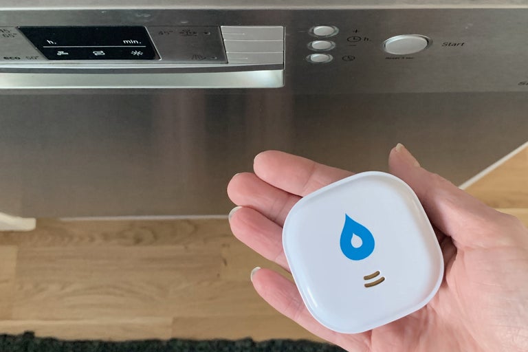 En hand håller en vattenvarnare framför en diskmaskin