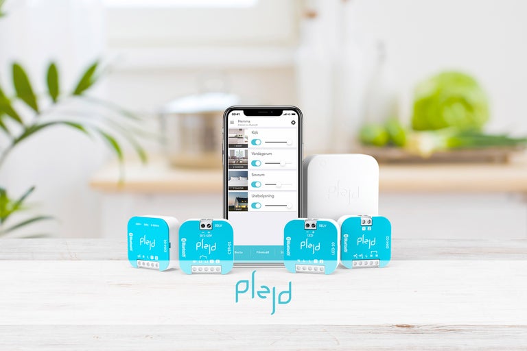 Plejd Smart Home System med smartphone-app och olika moduler i en köksscen.