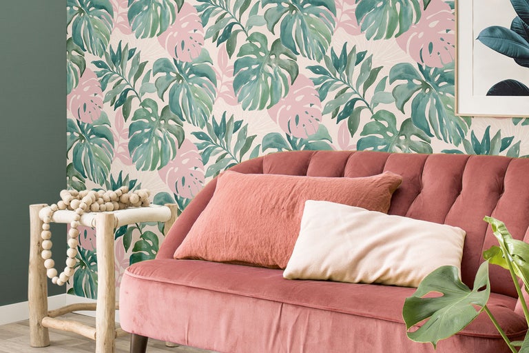 Vardagsrum med soffa, kuddar och blommig tapet i tropisk stil.