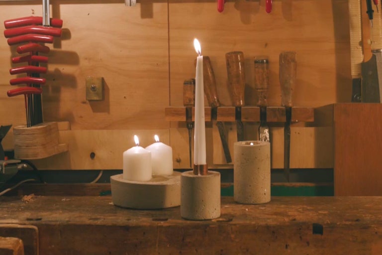 Dekorativa ljusstakar i betong med brinnande ljus på en arbetsbänk