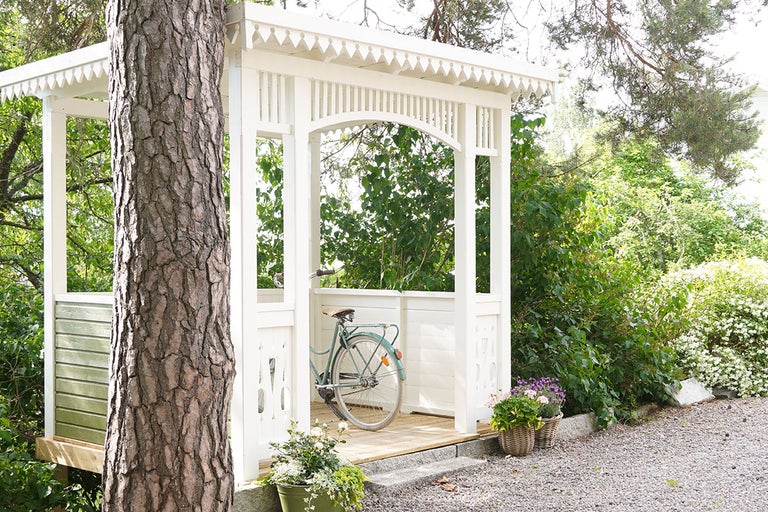 Trädgårdspaviljong med cykel och växter i trädgården