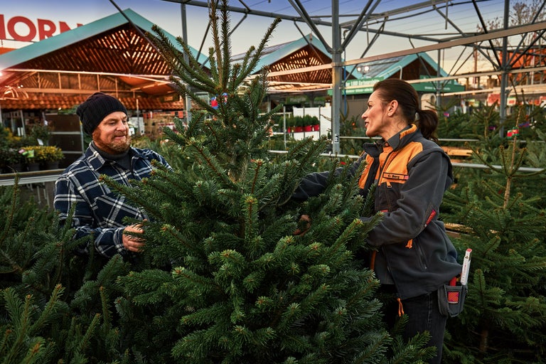 Kund och Hornbach-anställd väljer en julgran utomhus.
