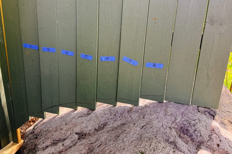 En grön trävägg med blå tejp och siffrorna två till åtta.