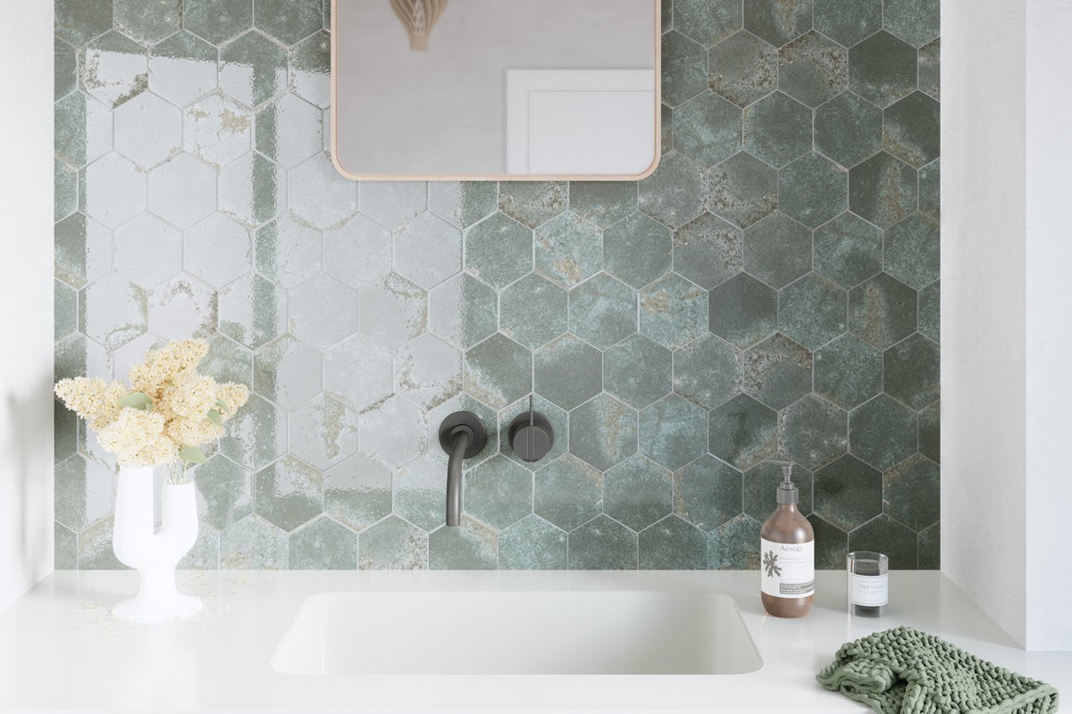 Tvättställ i badrum med hexagonala väggplattor, armatur, spegel, tvålpump, glas och handduk
