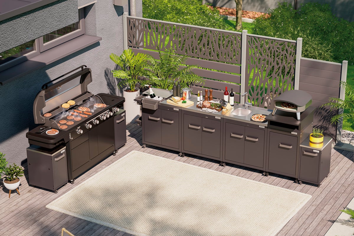 Komplett utekök med grill, diskho, arbetsytor och pizzaugn på en terrass