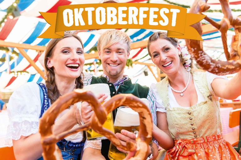 Tre personer i traditionella kläder firar Oktoberfest med öl och kringlor under bokstäverna Oktoberfest.