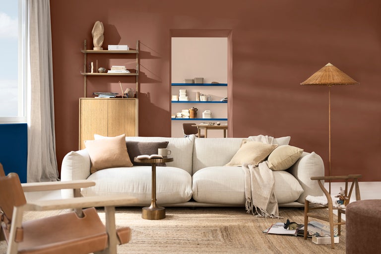 Vardagsrum med soffa, fåtölj, matta och hyllor mot en vägg