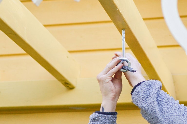 Person skruvar in ringskruv i träbjälke