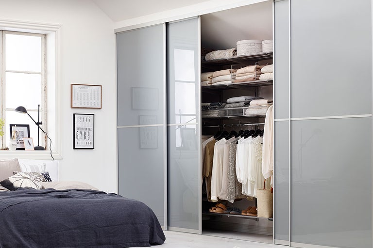 Sovrum med säng och skjutdörrsgarderob med inredning