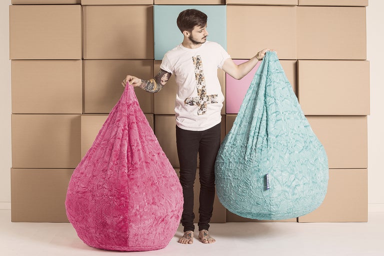 Man presenterar två droppformade sittsäckar mot en bakgrund av kartonger