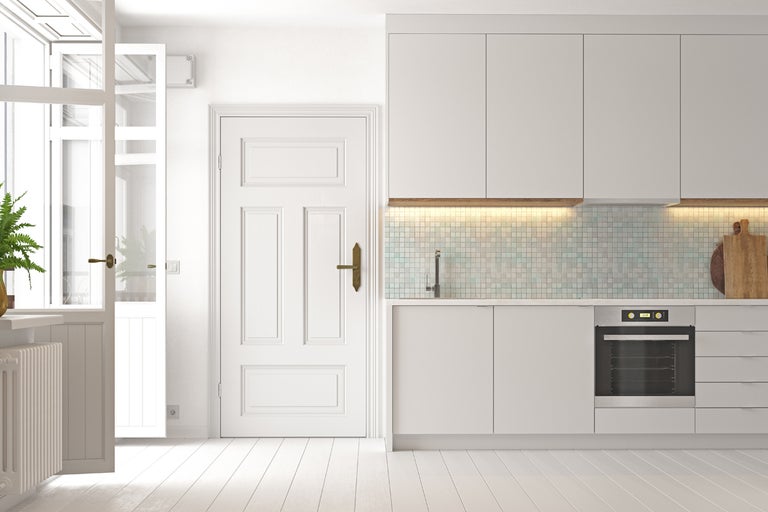 Ljust kök med inbyggda skåp, diskho, ugn och trädörr