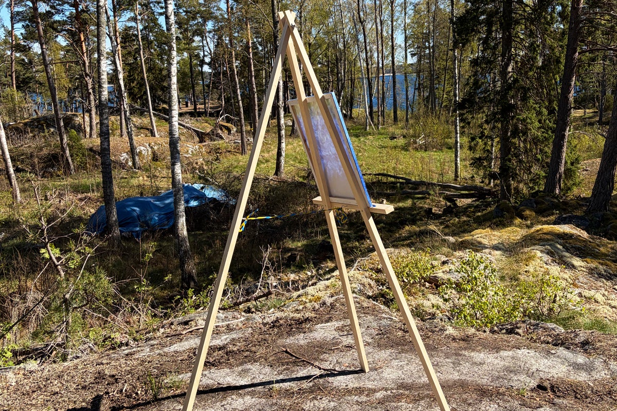 Trebent staffli av ljust trä uppställt utomhus på stenig skogsmark.