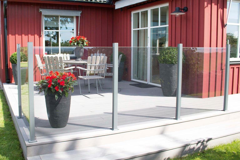 Terrass med glasräcke, bord, stolar och blomkrukor