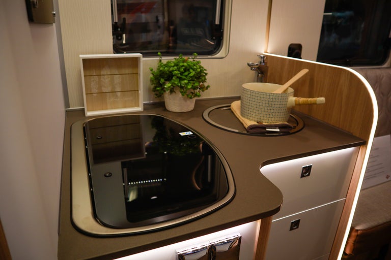 Kompakt kokvrå med spishäll, diskho och bänkskiva i en husbil