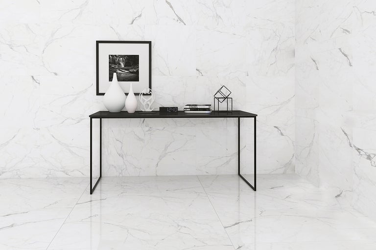 Ljust rum med golv- och väggplattor i marmorimitation samt svart bord med dekoration