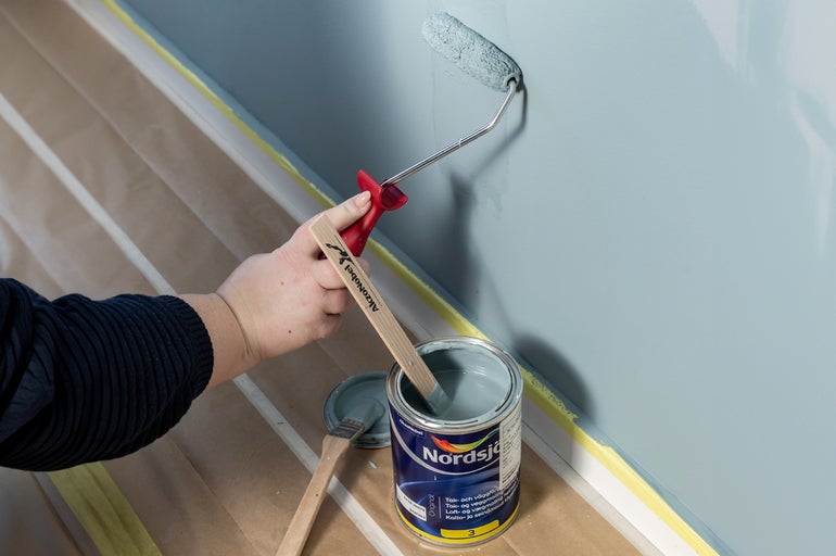 Målning av en vägg med roller och färgburk från Nordsjö