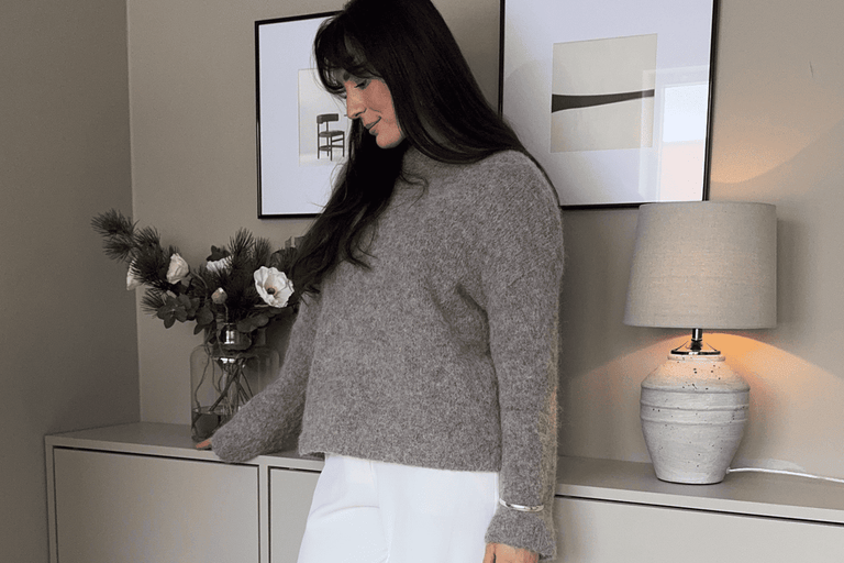 Vardagsrum med byrå, dekoration, lampa och kvinna i tröja