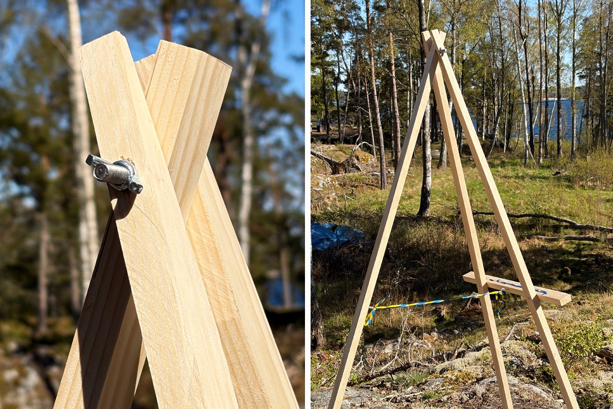 Trefotskonstruktion av träribbor, fäst upptill med en vingmutter, placerad i en naturlig utomhusmiljö.