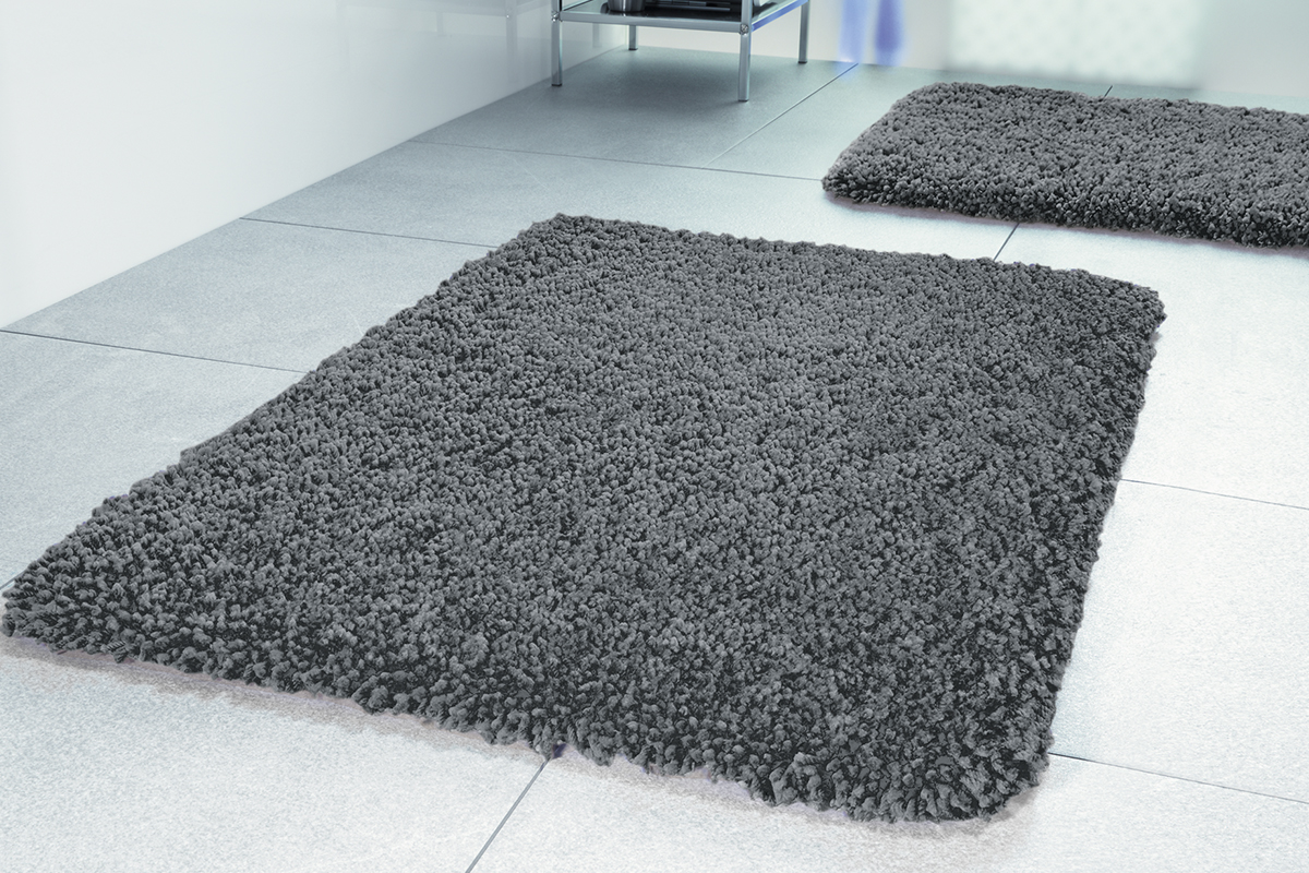 Två grå badrumsmattor på ljusgrått klinkergolv.