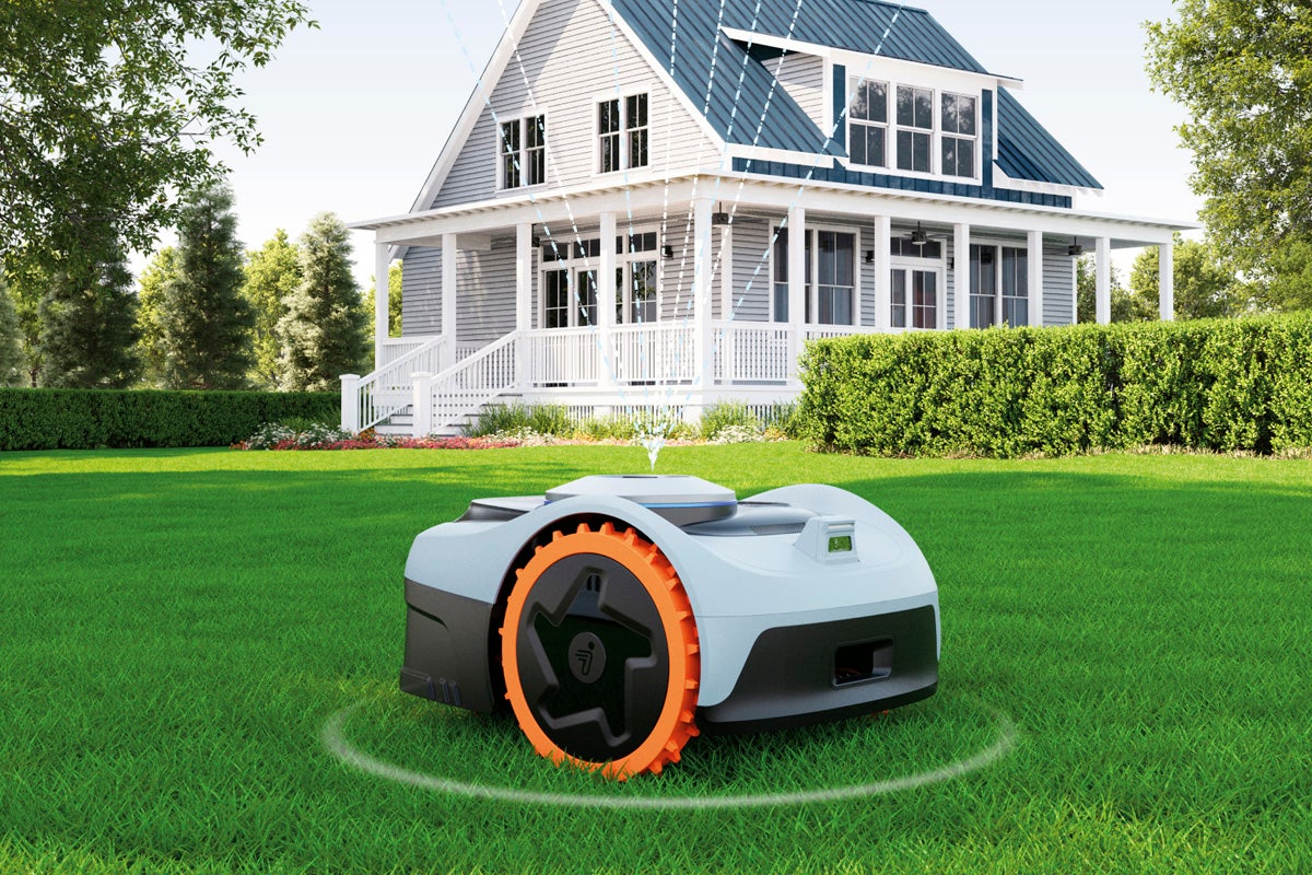 Robotgräsklippare på gräsmatta framför ett bostadshus