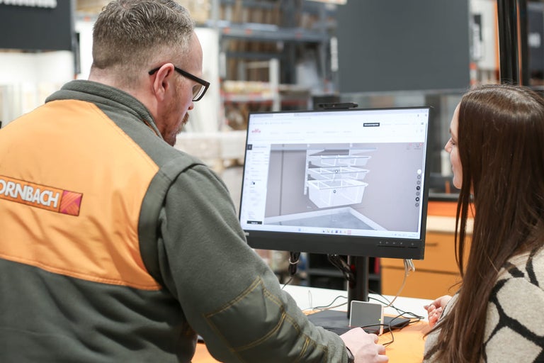 En Hornbach-anställd ger råd till en kund om planering av ett skåpssystem på datorn