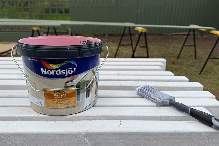 Färghink och pensel på ett träbord för utomhusbruk