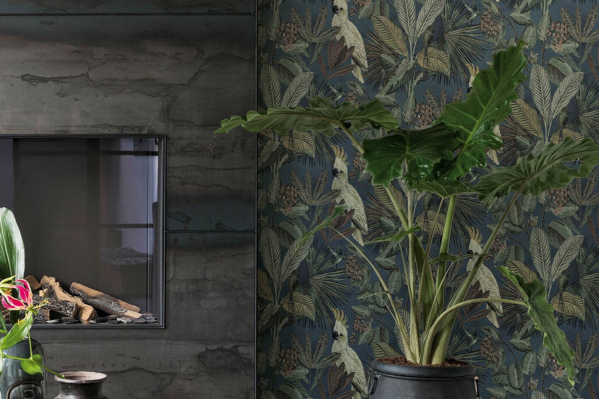 Vardagsrum med öppen spis, växt och djungeltapet med kakadu-motiv