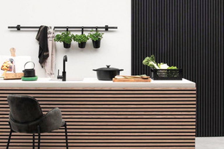 Ljust kök med diskho, kran, kastrull, örter och stol