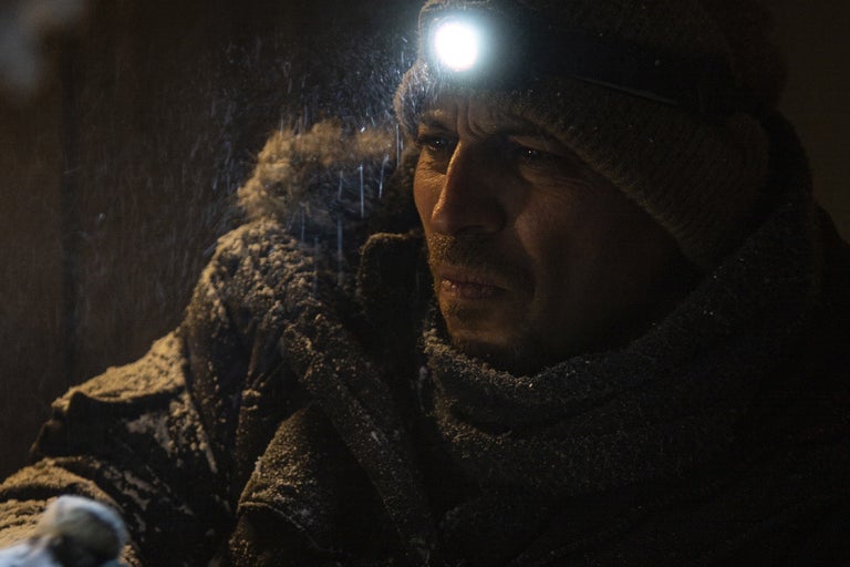 Porträtt av en man med pannlampa i snön