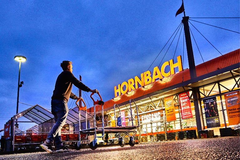 En man skjuter en vagn framför en Hornbach-butik.