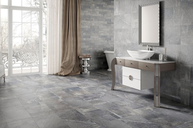 Modernt badrum med gråa kakelplattor, handfat och spegel