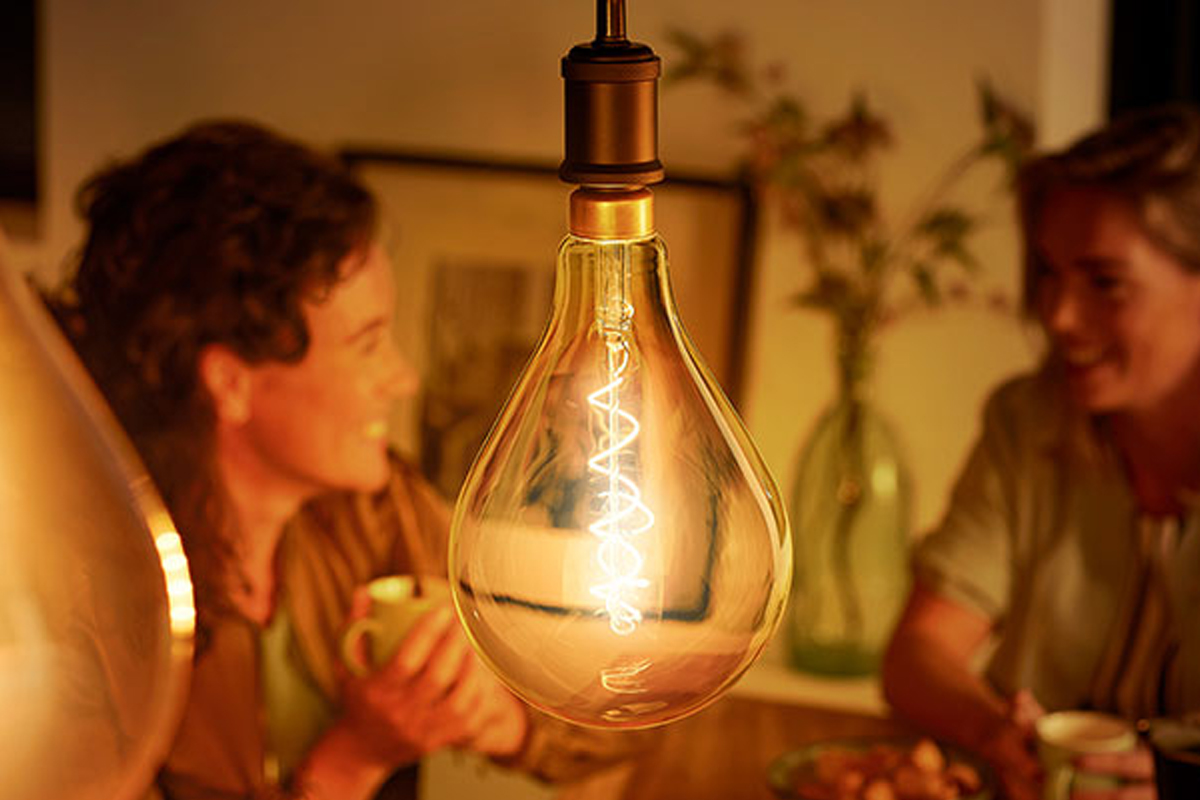 Dekorativ glödlampa i vardagsrum med personer i bakgrunden