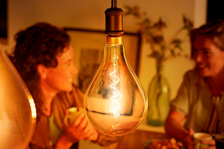 Dekorativ glödlampa i vardagsrum med personer i bakgrunden