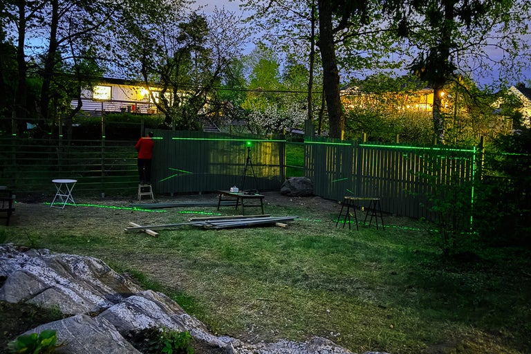 Byggande av trädgårdsstaket med laserpass i trädgården.