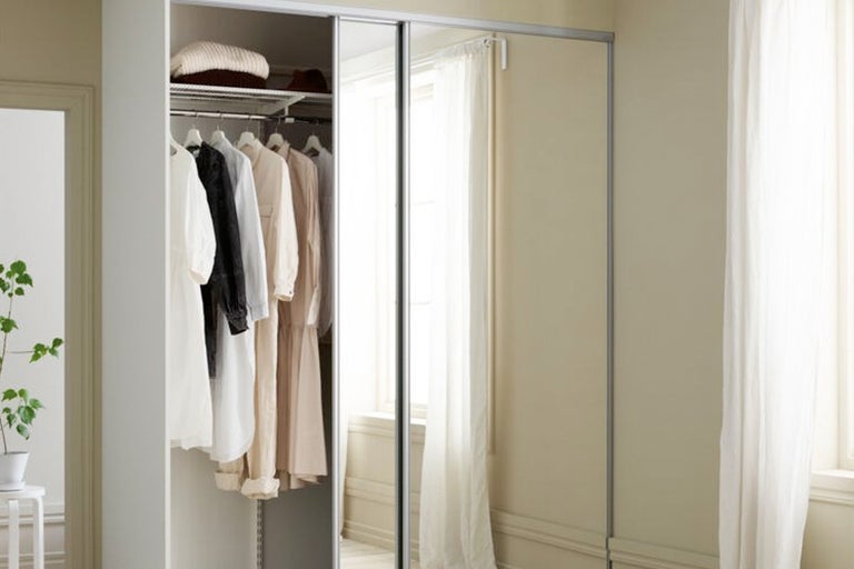 Öppen garderob med kläder och skjutdörrar med spegel