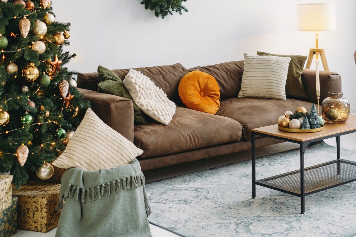 Juldekorerat vardagsrum med brun soffa, soffbord och julgran