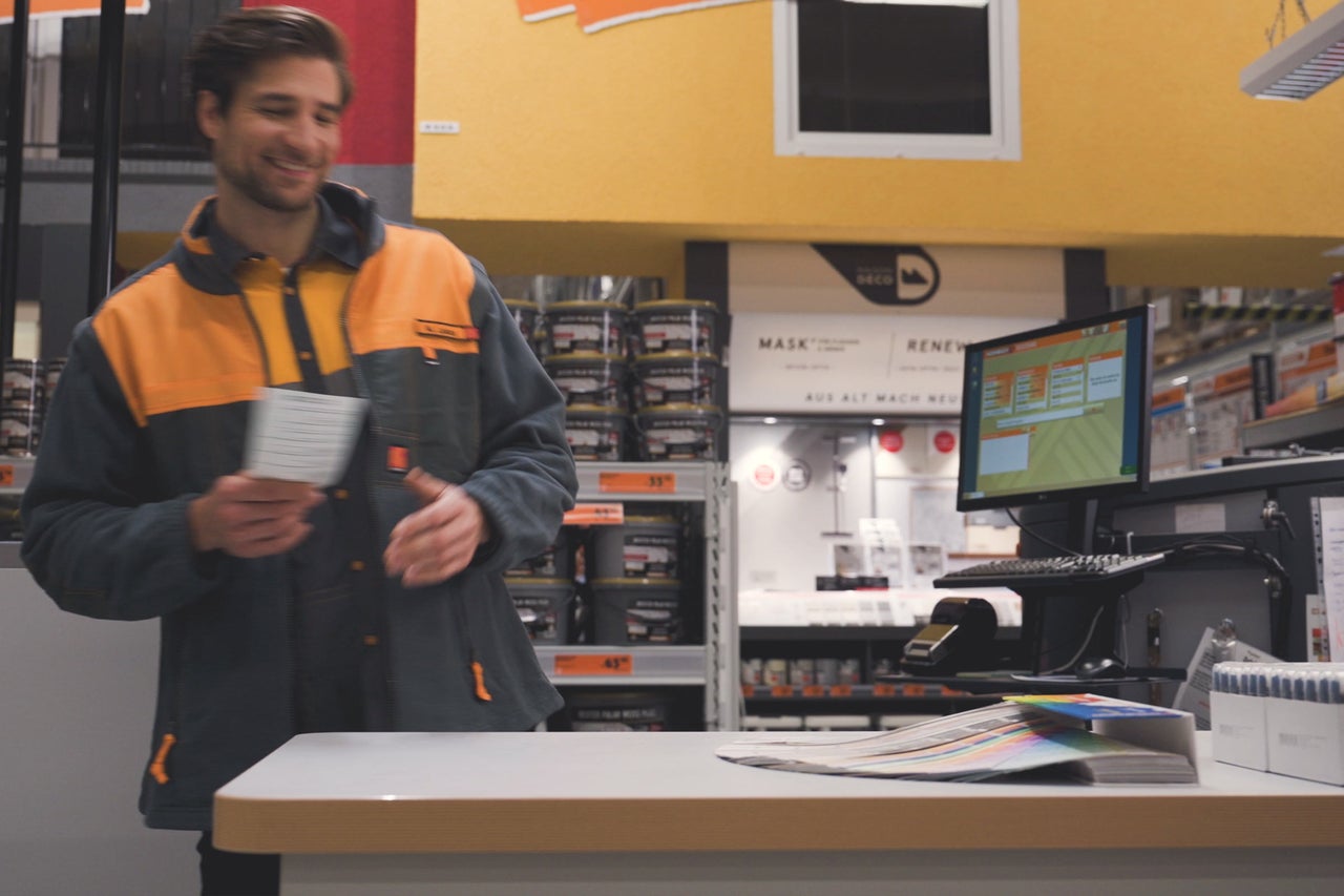 En Hornbach-anställd med färgfläktar vid färg blandningsmaskinen