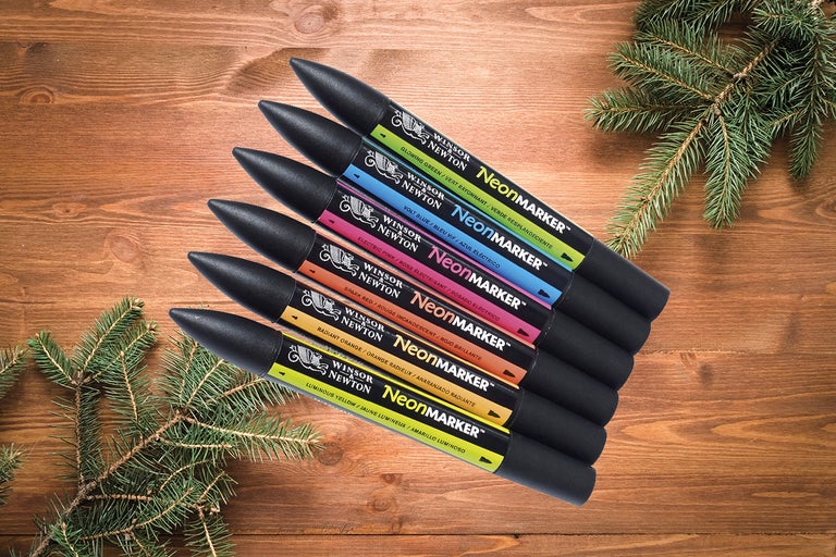 Sex Winsor Newton neonmarkörer på ett träbord.