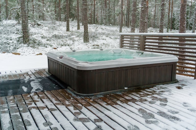 Bubbelpool på trädäck i en snöig skog