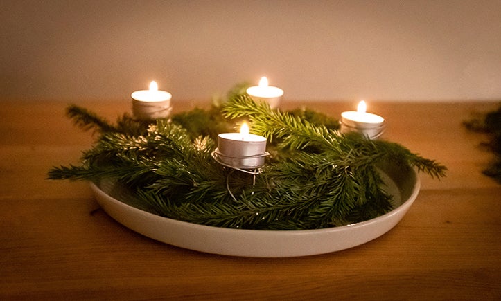 Adventskrans med fyra värmeljus och grangrenar på en tallrik