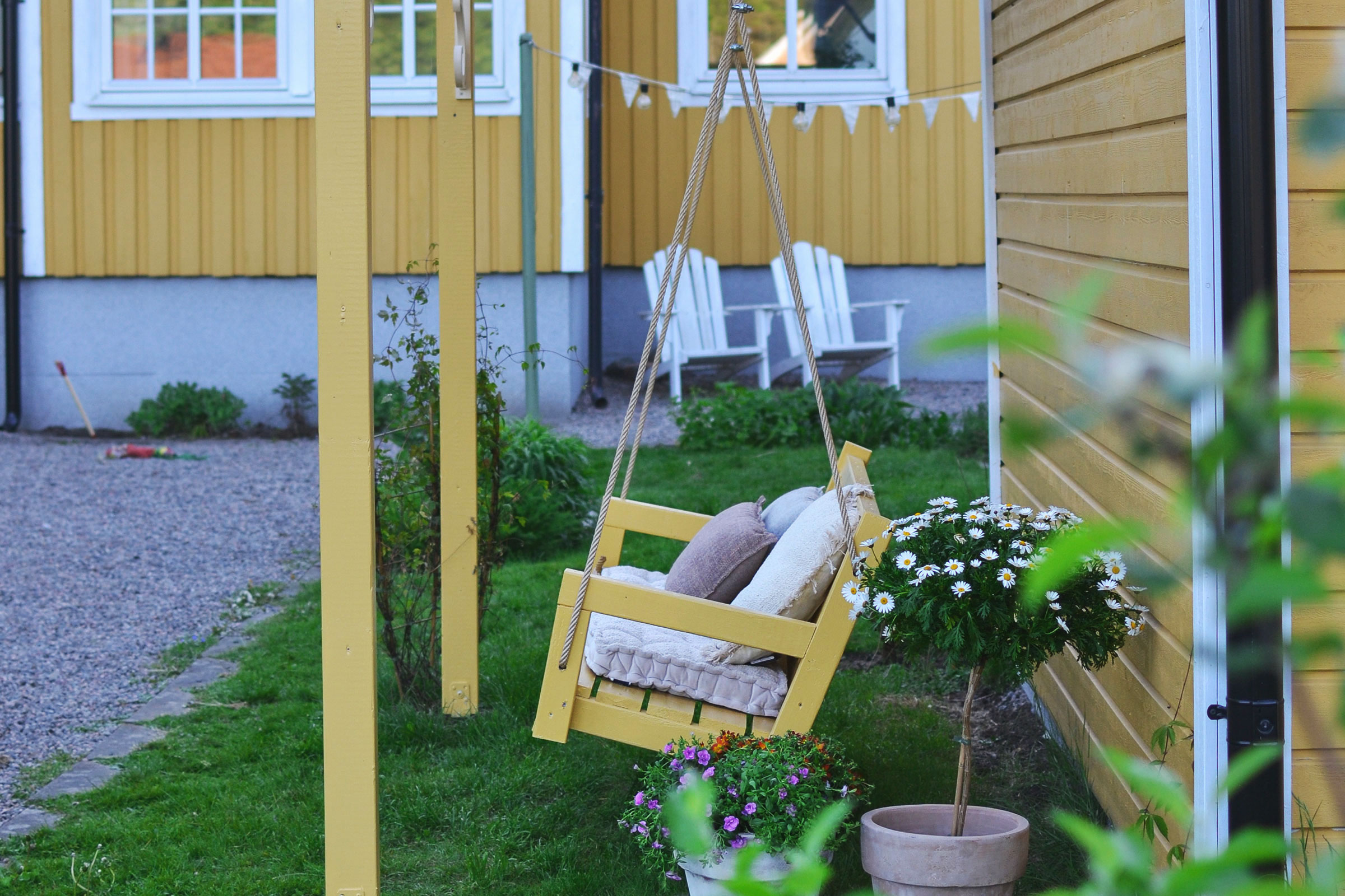 Trä gungställning med kuddar i trädgården
