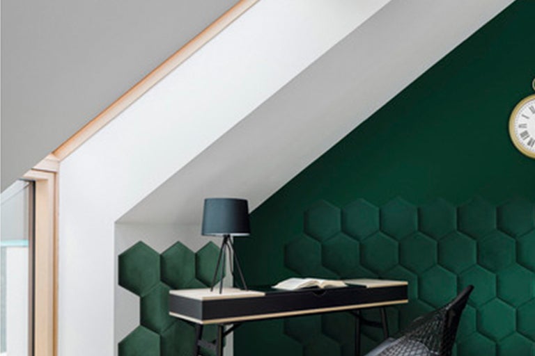 Vindsrum med skrivbord, lampa, klocka och hexagonformade väggpaneler