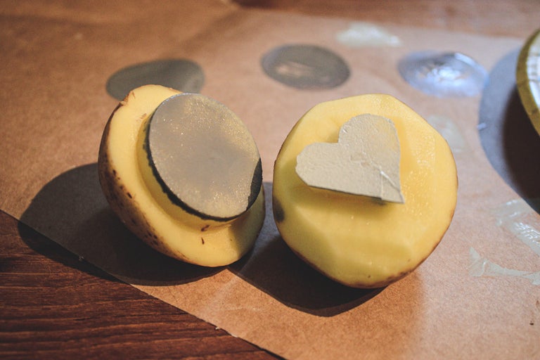 Två halva potatisar med utskurna former för stämpling